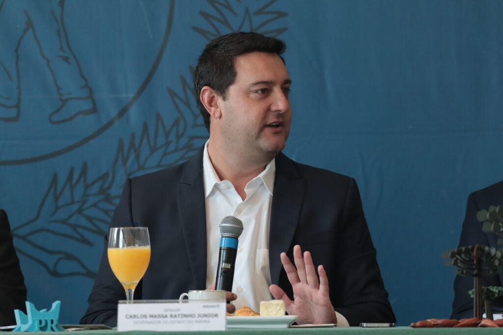 O governador Carlos Massa Ratinho Junior fala na mesa de um evento