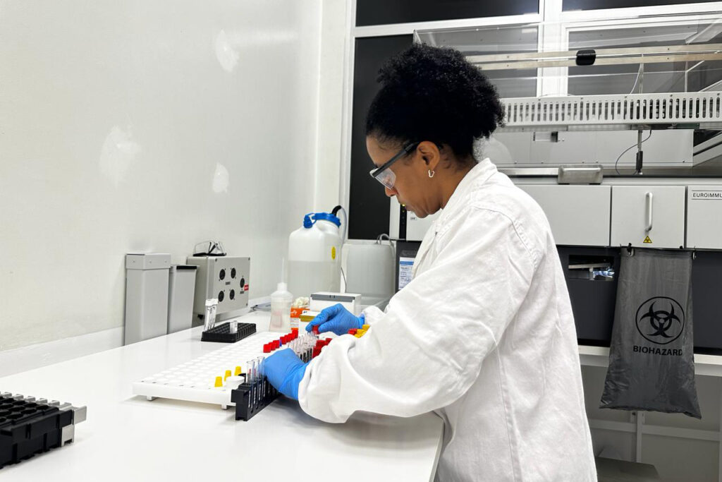 Mulher com equipamento de segurança manipula amostras em laboratório