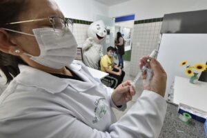Enfermeira usa de seringa com agulha para extrair vacina de frasco