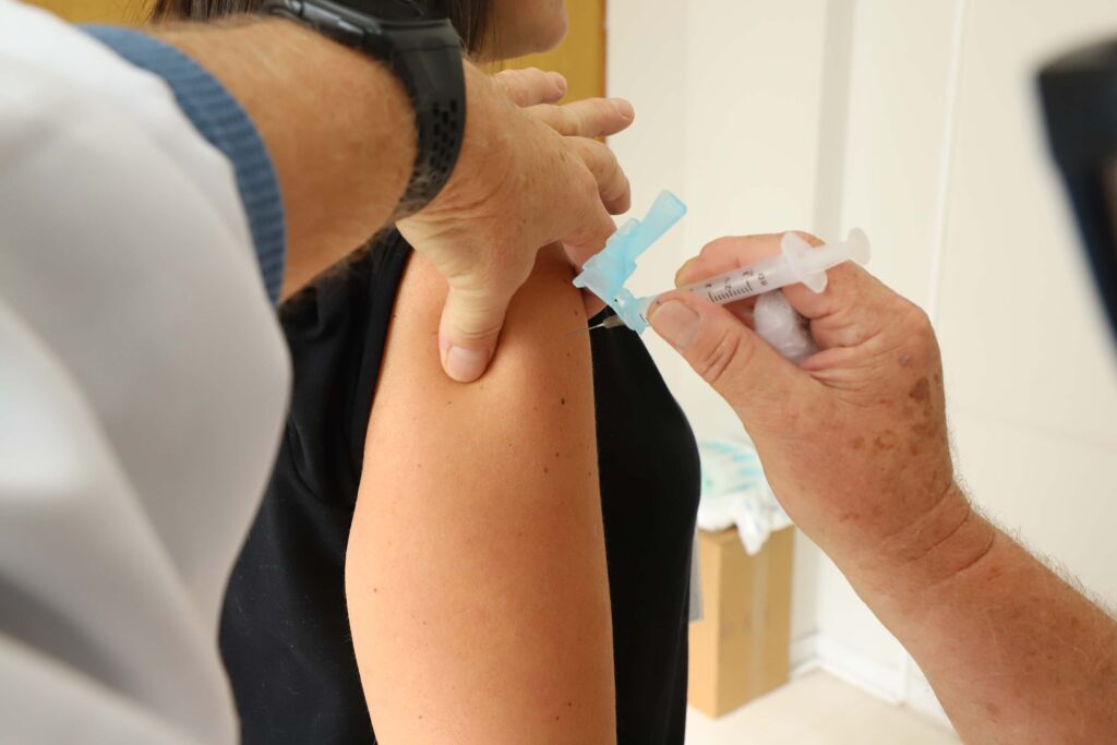 Agulha com vacina é aplicada em braço de paciente