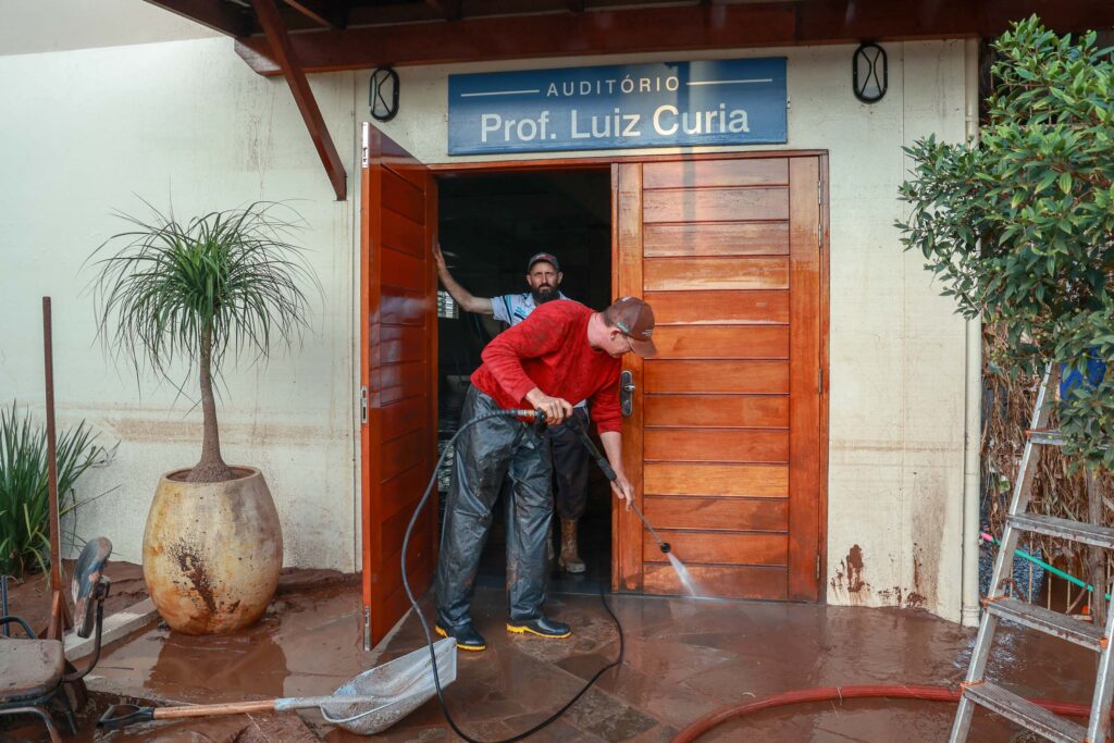 Homem usa de máquina de água pressurizada para limpar fachada de escola