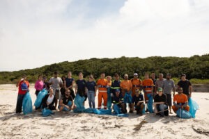 voluntários posam na praia com sacolas de lixo