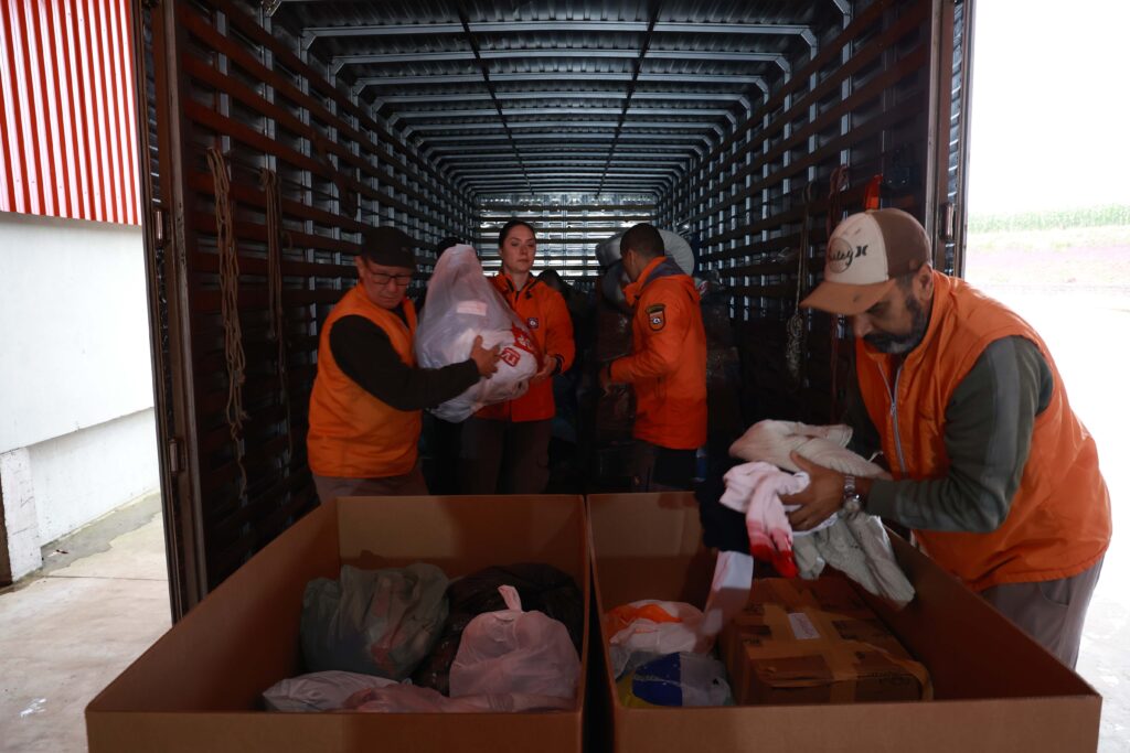 Voluntários carregam caminhão com doações.