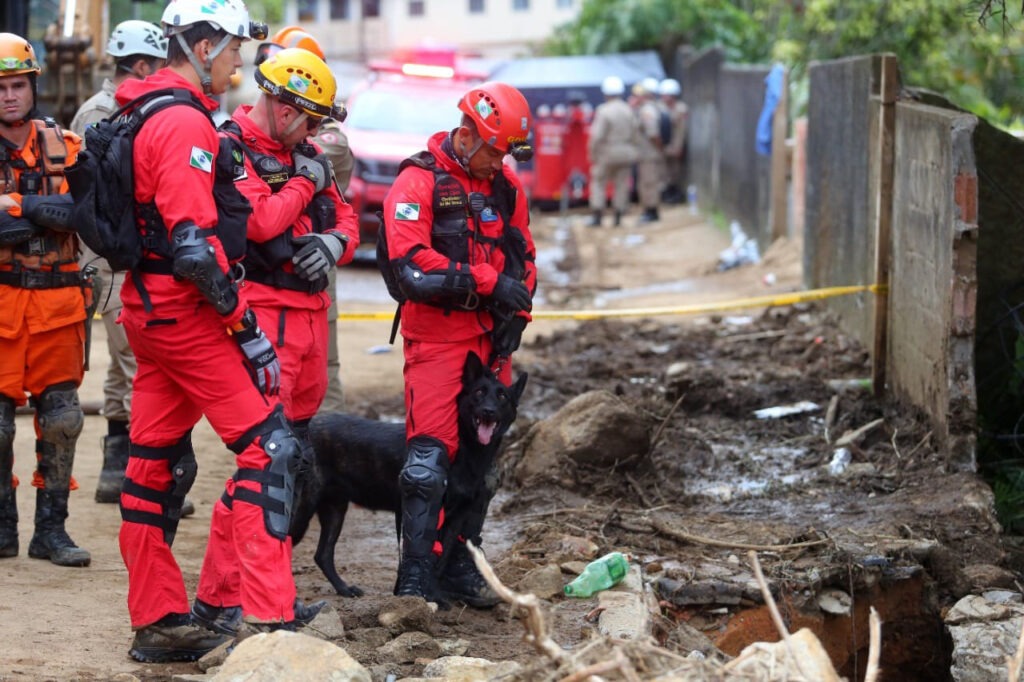 Bombeiros olham para dentro de buraco em via