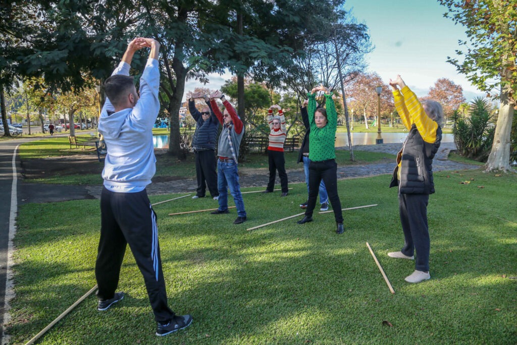 Idosos fazem atividade de alongamento em parque