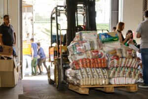 Empilhadeira carrega sacas com doações de alimentos não perecíveis
