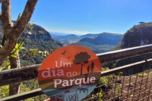 Vista panorâmica de montanhas com uma placa em primeiro plano escrito: Um dia no parque