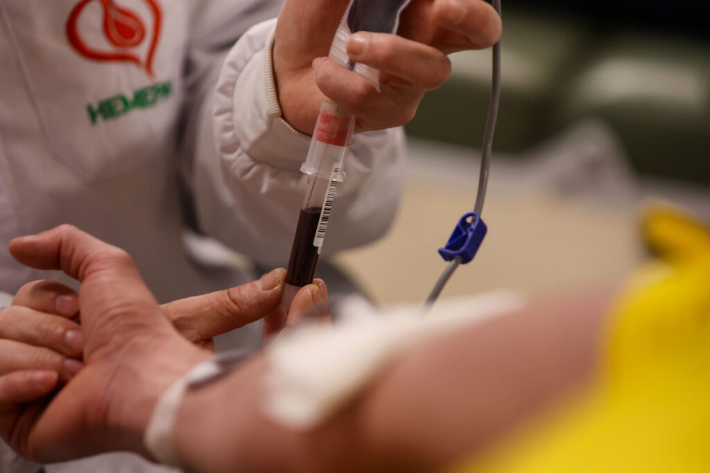 Profissional de saúde de jaleco coleta sangue de voluntário