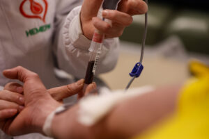 Profissional de saúde de jaleco coleta sangue de voluntário