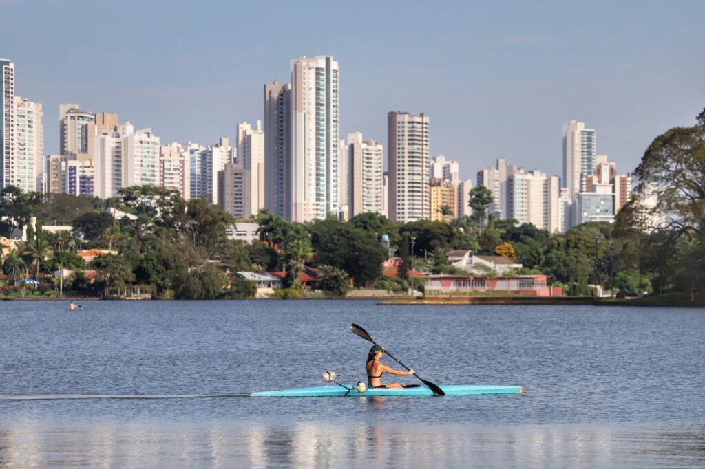 Em primeiro plano, temos o Lago Igapó. Nele, uma pessoa rema em um caiaque. Ao fundo, o skyline de Londrina. Foto para ilustrar o texto sobre as eleições para a prefeitura de Londrina.