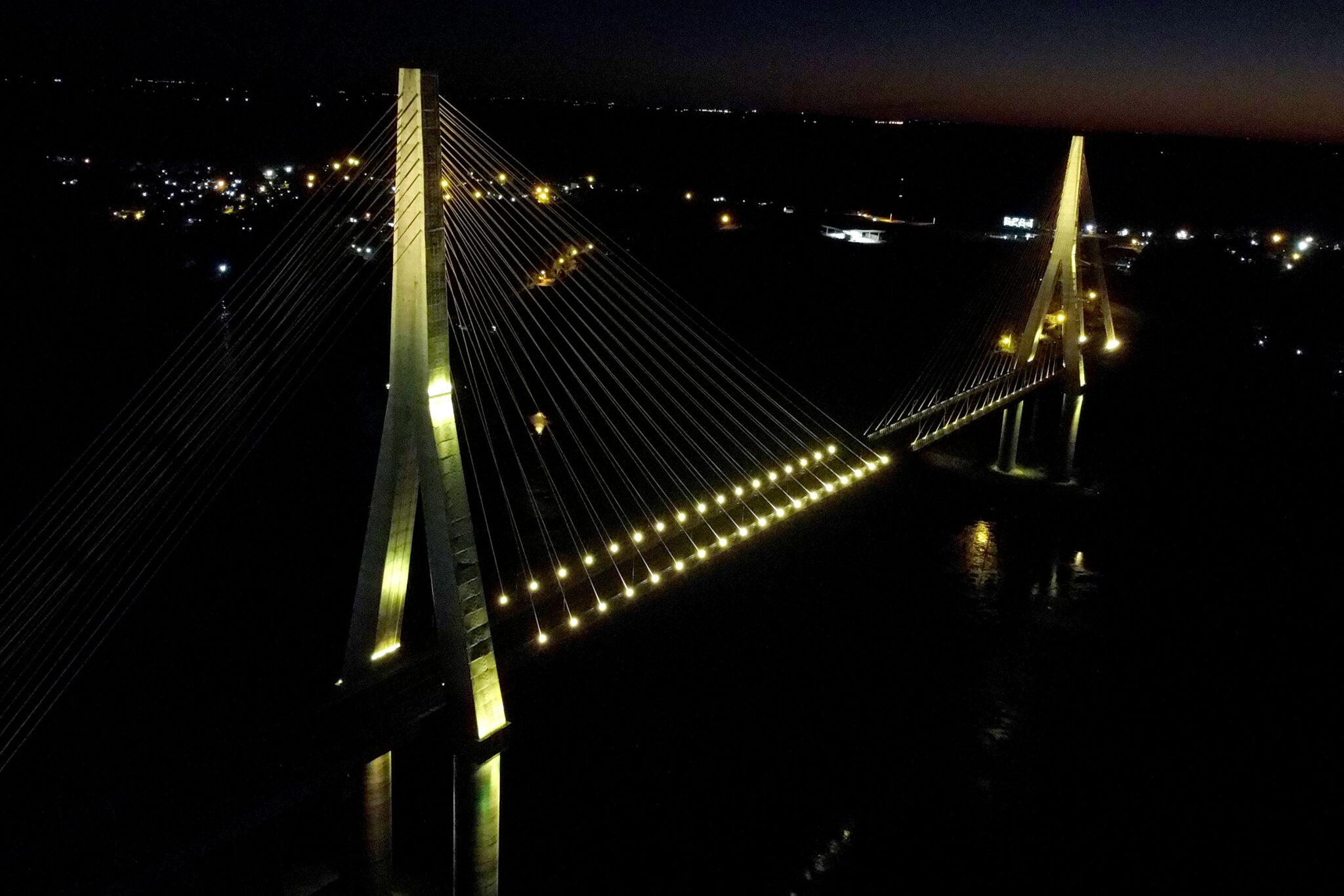 Imagem aérea e noturna da Ponte da Integração com iluminação amarela