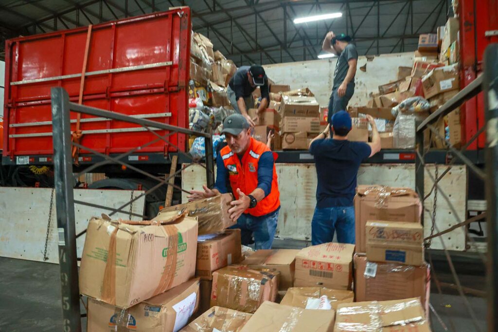 Pessoas movimentam caixas de papelão entre prateleiras