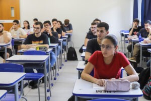 Alunos sentados em mesas de sala de aula