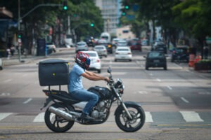 Motociclista com baú equipado em motocicleta atravessa cruzamento