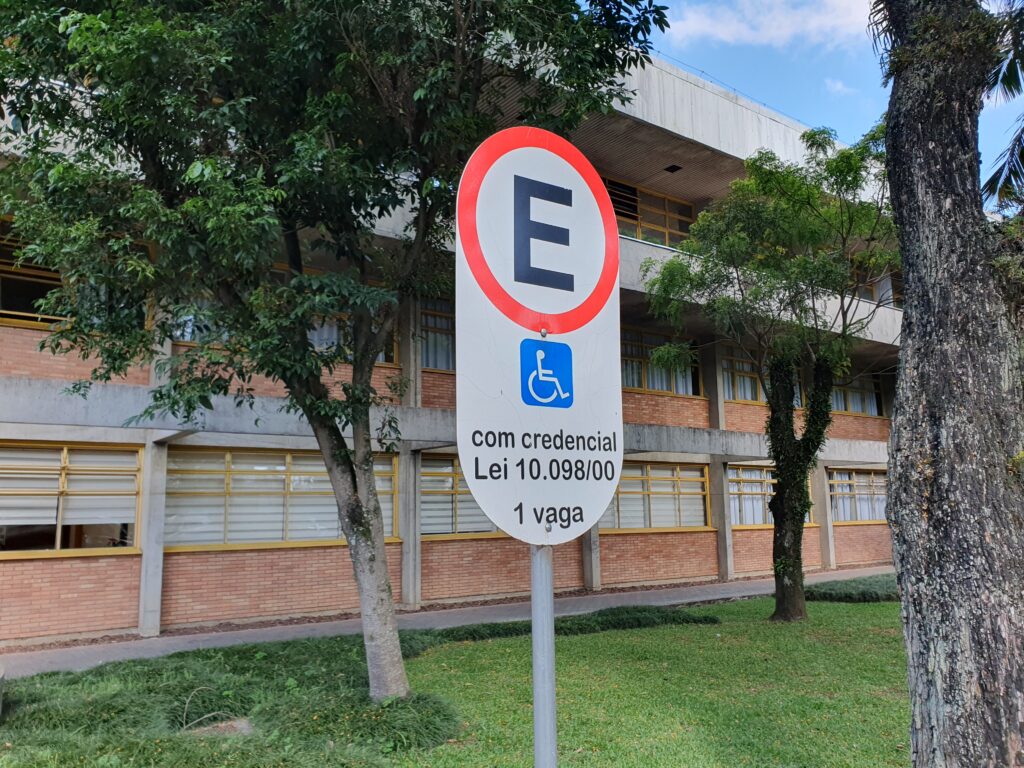 Placa de metal indicando que vaga de estacionamento é de uso reservado para pessoas com deficiência