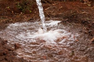 Água saindo de perfuração na terra