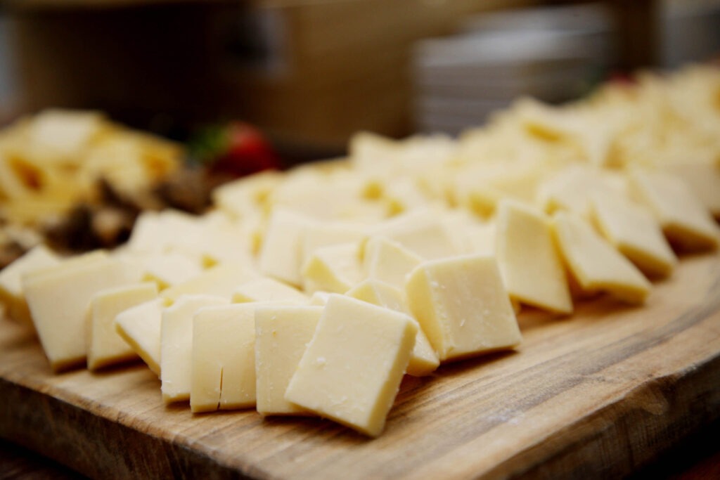 Queijo cortado em fatias quadradas em cima de uma tábua de madeira