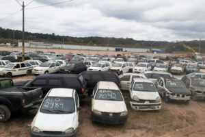 Pátio de carros com códigos escritos nos vidros dianteiros.