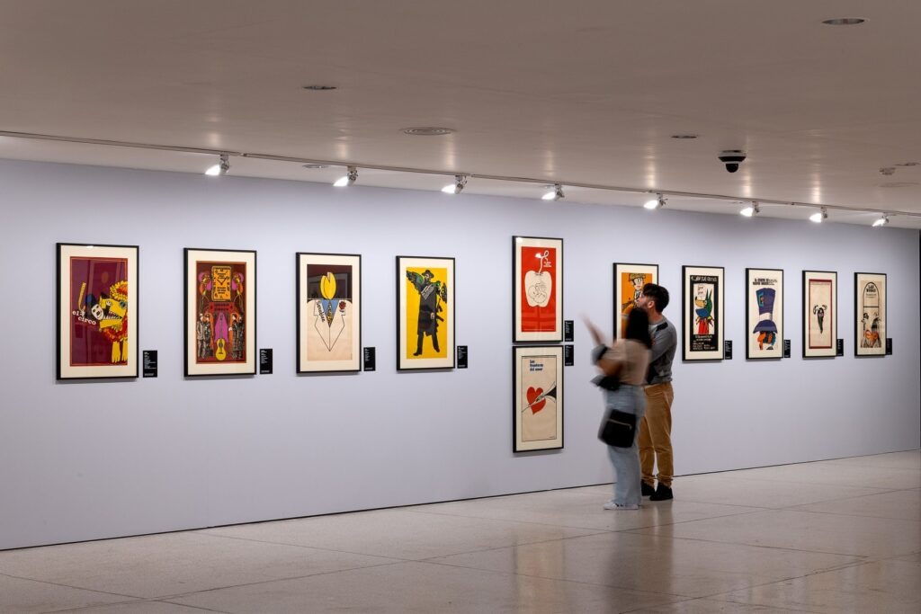 Pessoas olham a exposição de cartazes de cinema cubano que inspirou a oficina de cinema do Museu Oscar Niemeyer