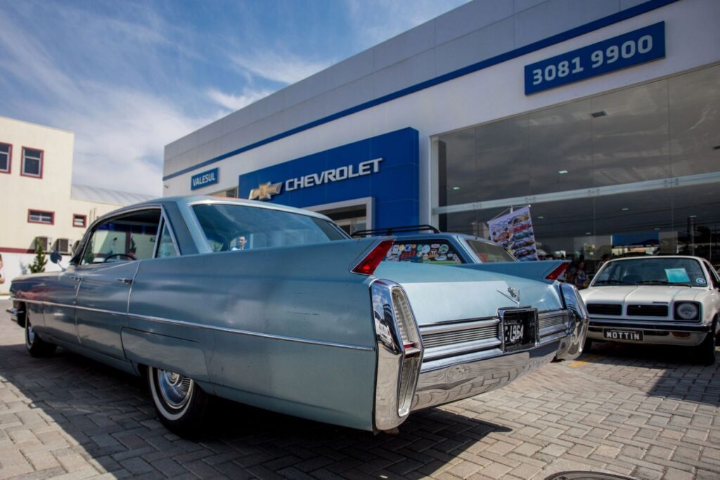 Carro antigo em frente a uma concessionária da rede Chevrolet
