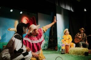 Atores com fantasias coloridas apresentam uma peça infantil
